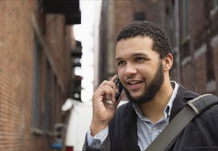 Mixed race businessman talking on cell phone in city