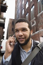 Mixed race businessman talking on cell phone in city