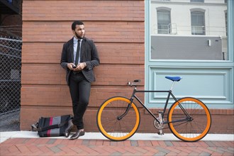 Mixed race businessman with bicycle on urban sidewalk