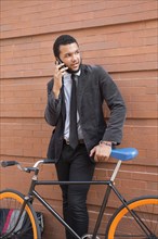 Mixed race businessman with bicycle outdoors