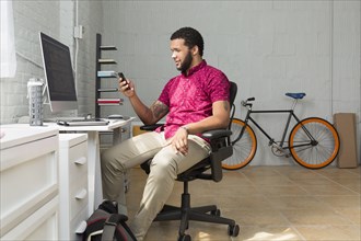 Mixed race businessman using cell phone at desk