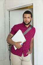 Mixed race businessman holding binder in doorway