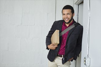Mixed race businessman holding box in doorway