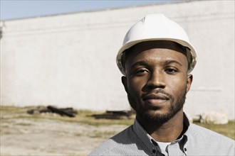 Close up portrait of Black man wearing hard-hat at construction site
