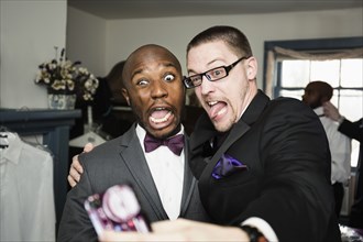 Groom and groomsman taking silly self-portrait