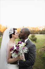 Newlywed couple kissing in park