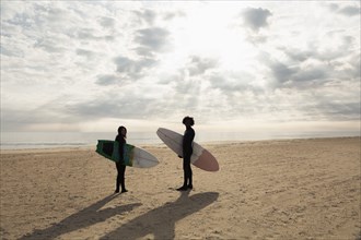 Surfers carrying boards on beach