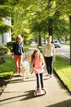 Caucasian family walking dog on suburban sidewalk