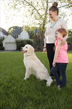 Caucasian mother and daughter with dog in park