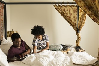 Couple and dog relaxing on bed