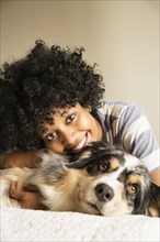 Mixed race woman laying with dog in bed