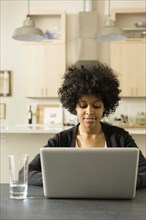 Mixed race woman using laptop at breakfast table