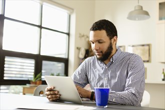 Mixed race businessman using tablet computer at desk