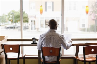 Black man reading paperwork in coffee shop