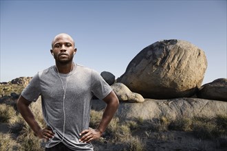 Black runner standing in rocky remote landscape