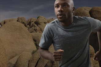 Black man running in rocky remote landscape