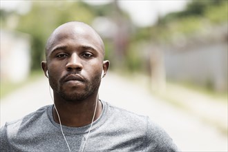 Black runner resting on city street with earbuds