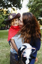 Mother kissing son dressed as cowboy for Halloween