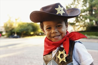 Mixed race boy in cowboy costume smiling outdoors