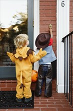 Boys in costumes trick or treating together on Halloween
