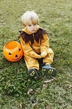 Caucasian boy in lion costume sitting on grass on Halloween