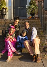 African American parents smiling with children in Halloween costumes