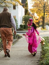 African American girl trick-or-treating with father on Halloween