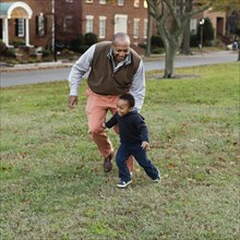 African American father and son playing in park