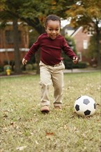African American boy playing soccer in park