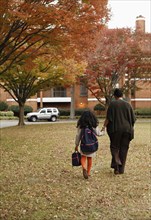 African American mother walking daughter to school