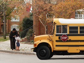 African American woman waiting with daughter for school bus