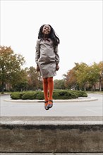 African American girl jumping on suburban street