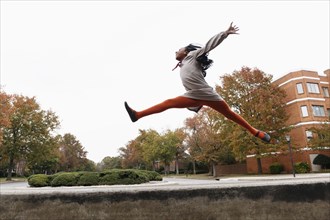 African American girl jumping for joy on suburban street