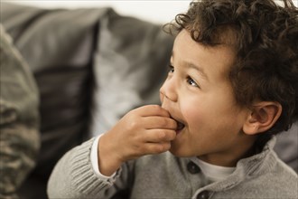 Close up of mixed race boy eating on sofa