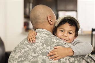 Mixed race soldier hugging son