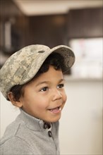 Mixed race boy wearing soldier cap