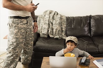 Mixed race father soldier and son relaxing in living room