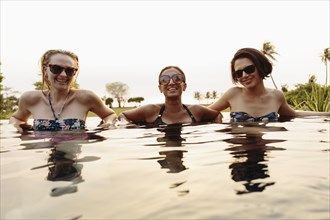 Smiling women relaxing in infinity pool