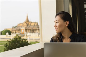 Asian businesswoman admiring view from cafe window