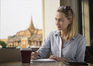 Caucasian businesswoman writing notes in cafe