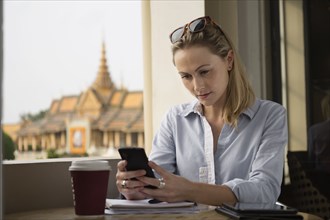 Caucasian businesswoman using cell phone in cafe