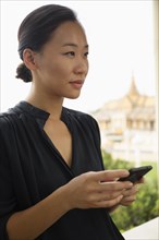 Asian woman using cell phone at window