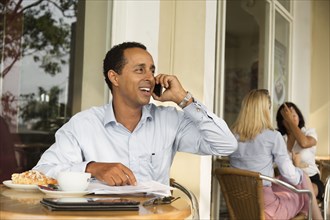 Businessman talking on cell phone in cafe