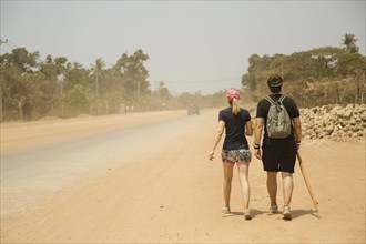 Caucasian couple walking on dirt road in remote field