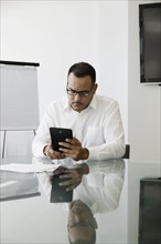Hispanic businessman using digital tablet in office