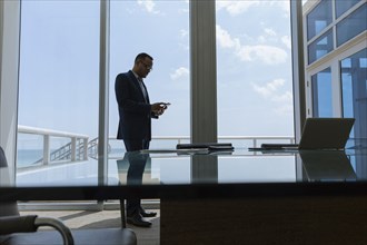 Hispanic businessman using cell phone in conference room
