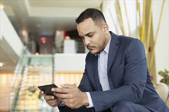 Hispanic businessman using digital tablet in hotel lobby