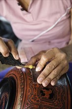 Asian artisan carving traditional design in workshop