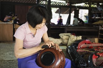 Asian artisan carving traditional design in workshop