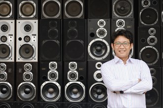 Asian man standing by stacked speakers